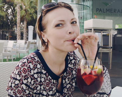 Lady drinks sangria from a goblet through a straw
