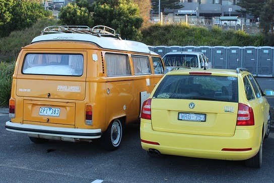 Orange van and yellow station wagon parked in a lot